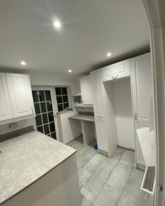 A new modern kitchen installation featuring white laminate flooring, grey kitchen countertops and white kitchen cabinets and cupboards.