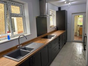 A new kitchen installation featuring new tiled flooring, grey kitchen cabinets and wooden worktops.