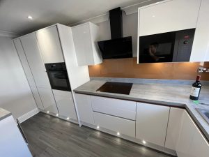 A new kitchen installation featuring integrated appliances, grey vinyl flooring and white kitchen cabinets and cupboards.