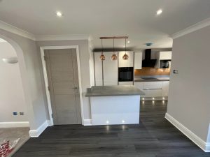 A new kitchen installation featuring integrated appliances, grey vinyl flooring and white kitchen cabinets and cupboards.