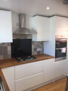 A new kitchen installation featuring integrated appliances installed in white cabinets and wooden kitchen worktops.