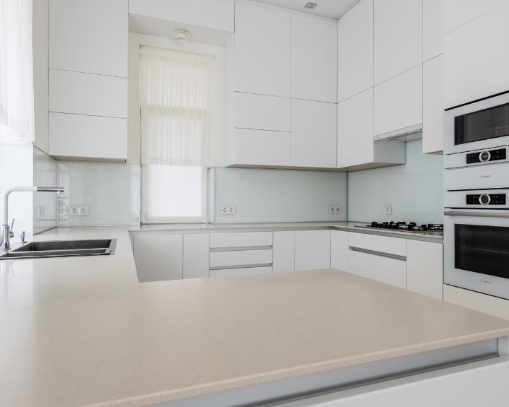 A modern kitchen with white cabinets and counter tops installed by Kitchen Fitters in Basingstoke.
