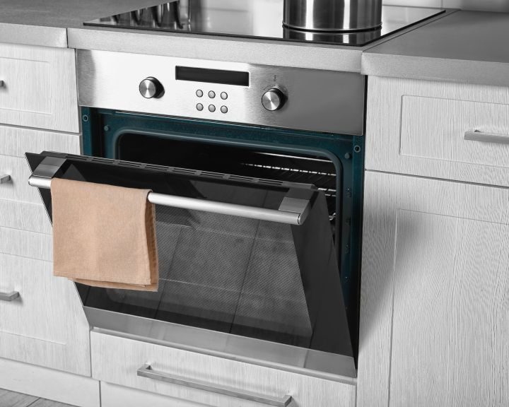 A stainless steel oven with a towel hanging on it in the kitchen.