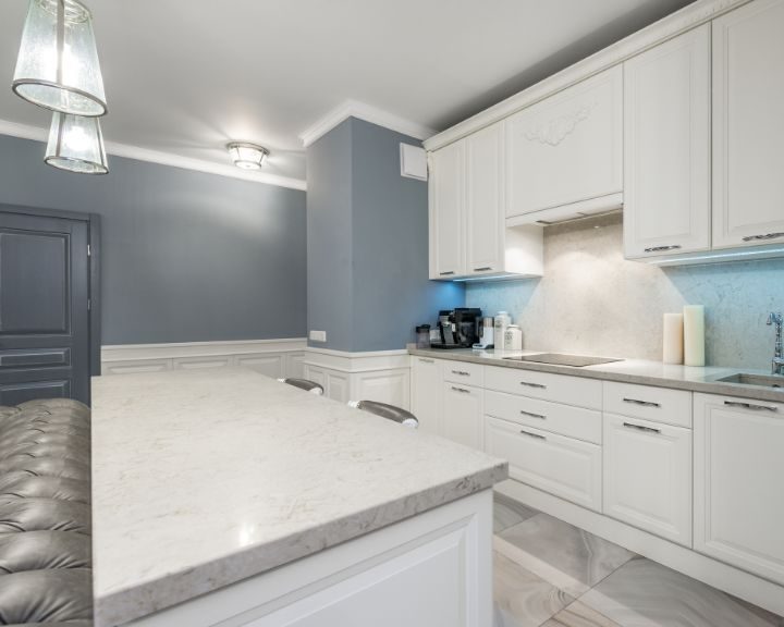 A contemporary kitchen featuring white cabinets and luxurious marble countertops, located in Basingstoke.