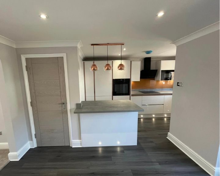 A new kitchen installation featuring white cabinets and cupboards, grey countertops, wall tiling and grey vinyl flooring.