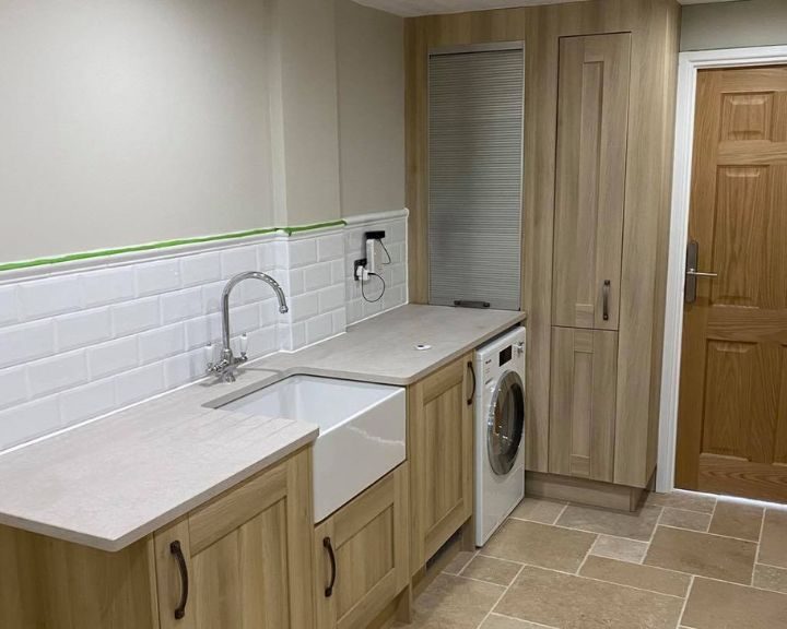 A new kitchen installation featuring white wall tiling and sandstone floor tiling.