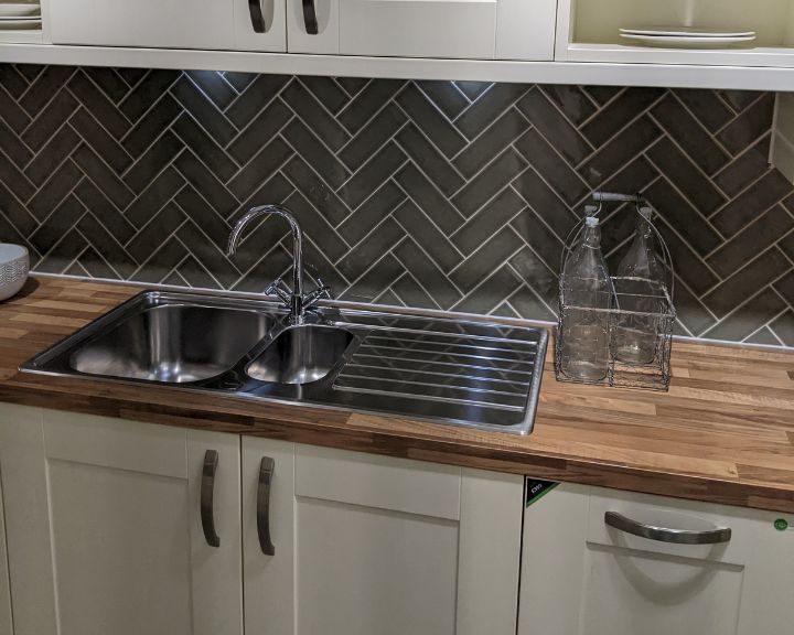 A kitchen installation featuring green herringbone wall tiling.